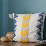 Dekoracyjna poduszka z geometrycznym wzorem i frędzlami na kanapie