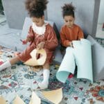 Dwie siostry bawiące się kreatywnie na dywanie w pokoju dziecięcym