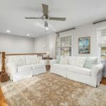 Jasny salon z białymi sofami i drewnianą podłogą