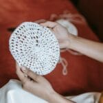 Dłonie kobiety trzymające ręcznie wykonane okrągłe szydełkowanie