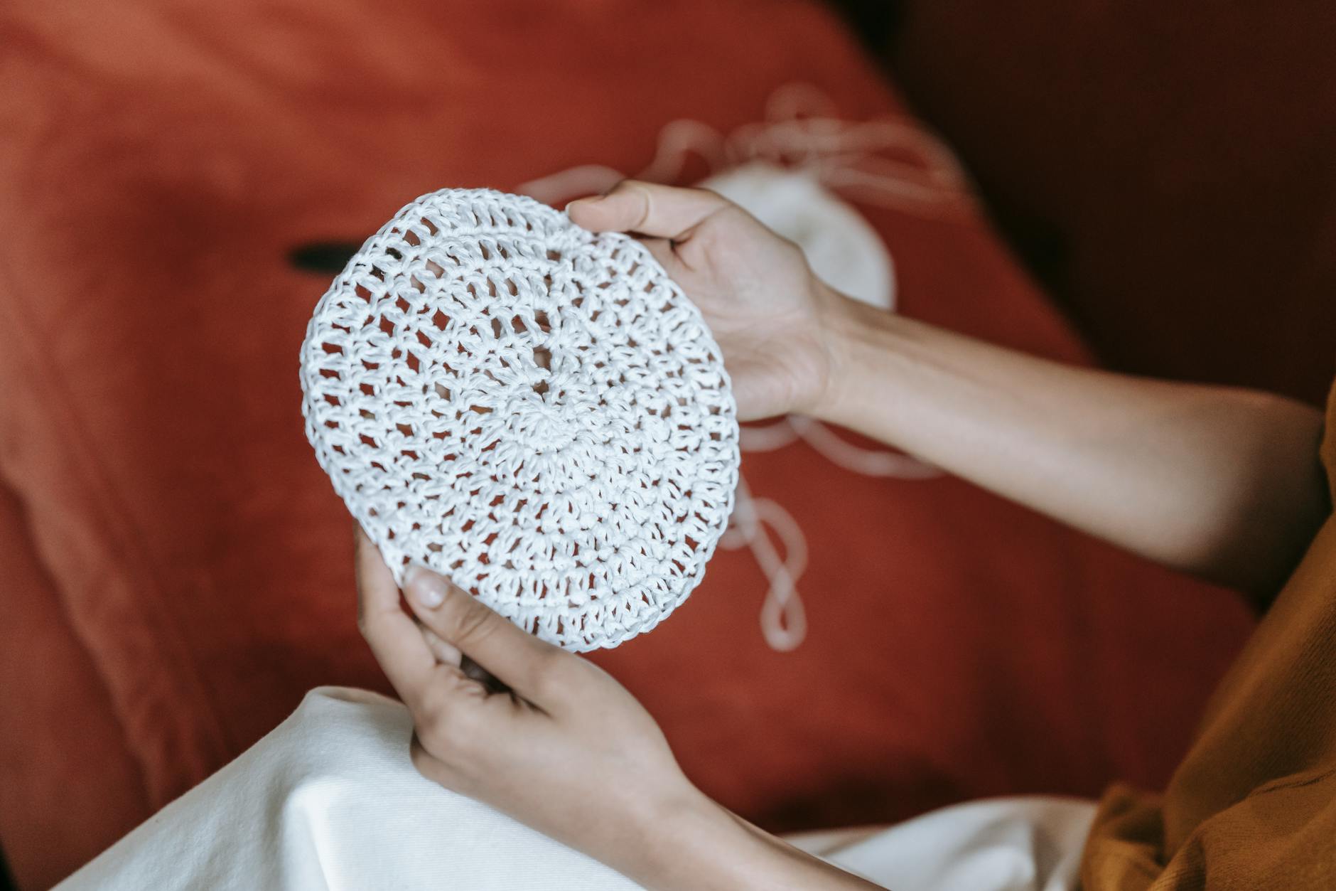 Dłonie kobiety trzymające ręcznie wykonane okrągłe szydełkowanie