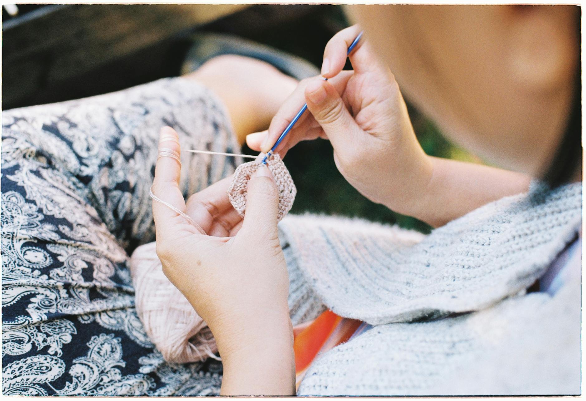 Kobieta szydełkuje na dworze, zbliżenie na fakturę robótki