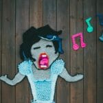 Kolorowy szydełkowy obraz śpiewającej kobiety z nutami na drewnie