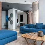 Nowoczesny salon z dużą niebieską sofą i minimalistycznymi dodatkami
