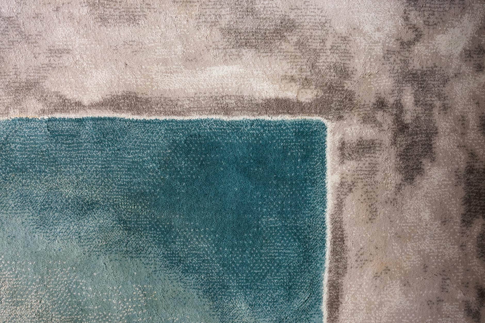 Zbliżenie na dywanik ze sznurka z turkusowym prostokątem na szarym tle