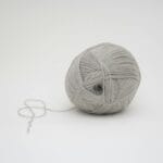 Zbliżenie na szarą włóczkę w kłębku na białym tle