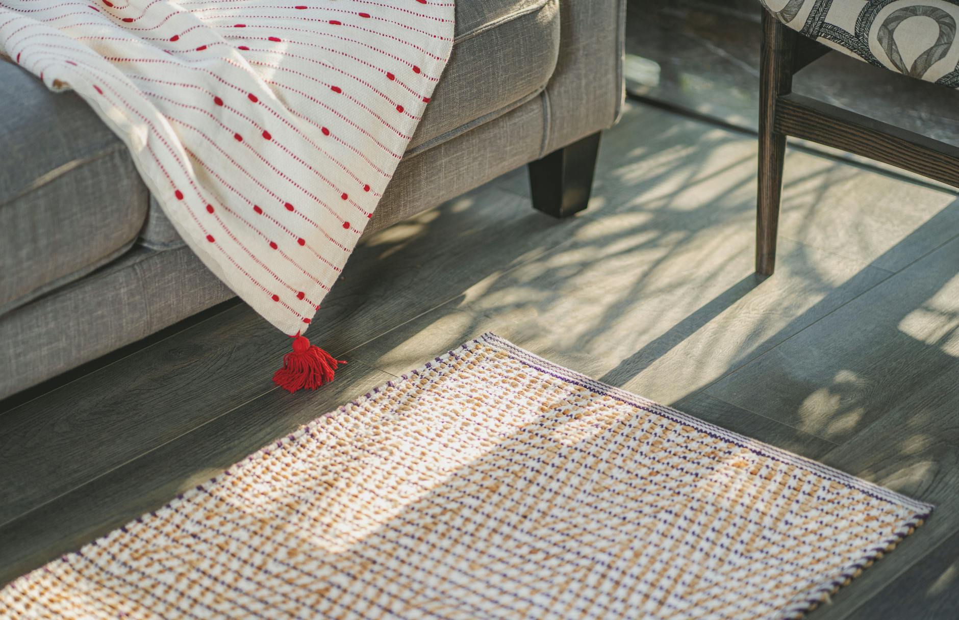 Jasny salon z szaryą sofą i plecionym dywanem ze sznurka bawełnianego