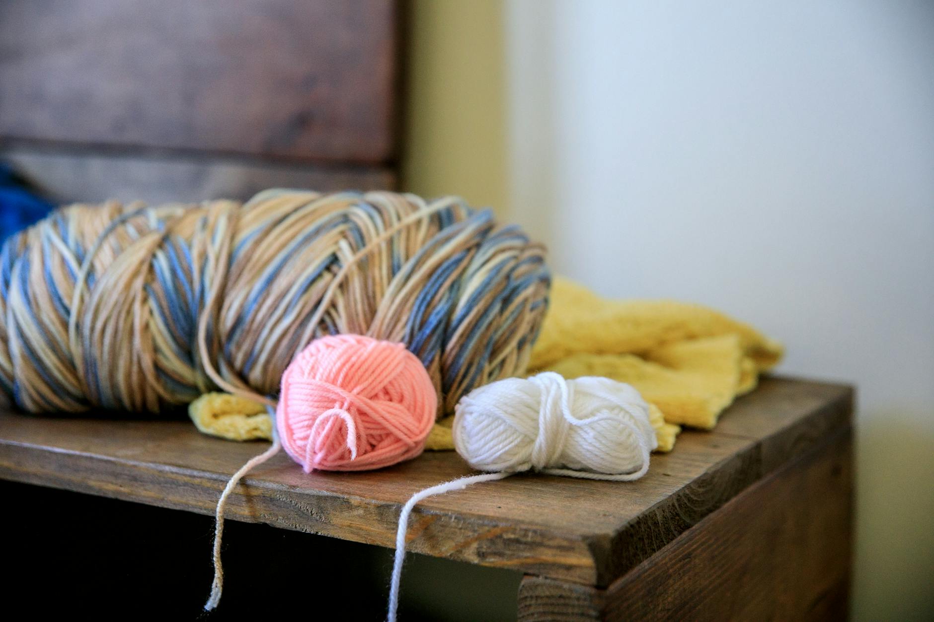 Kolorowe kłębki sznurka na drewnianym stole do robienia puf
