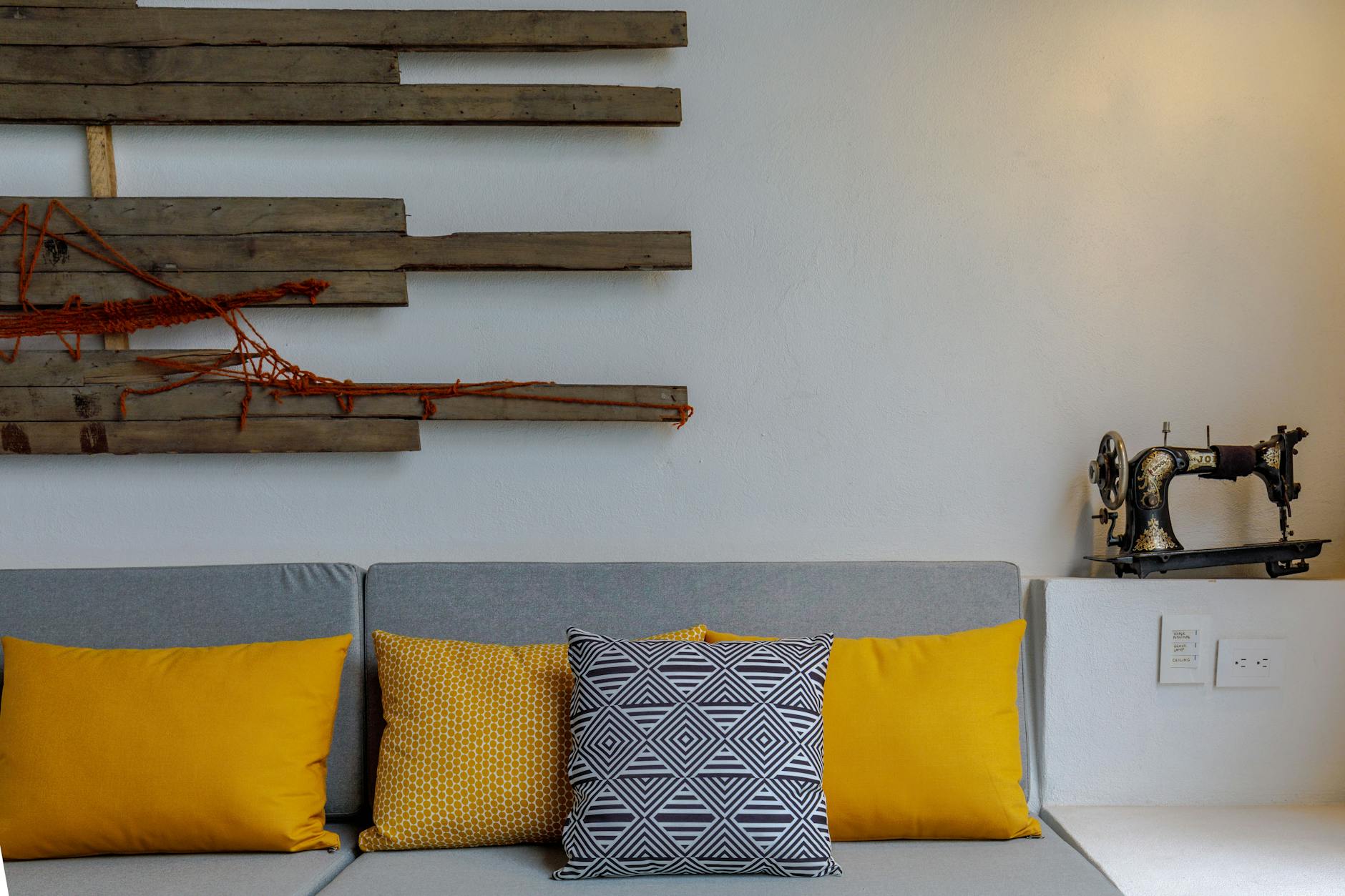 Kolorowe poduszki w nowoczesnym salonie obok starej maszyny do szycia