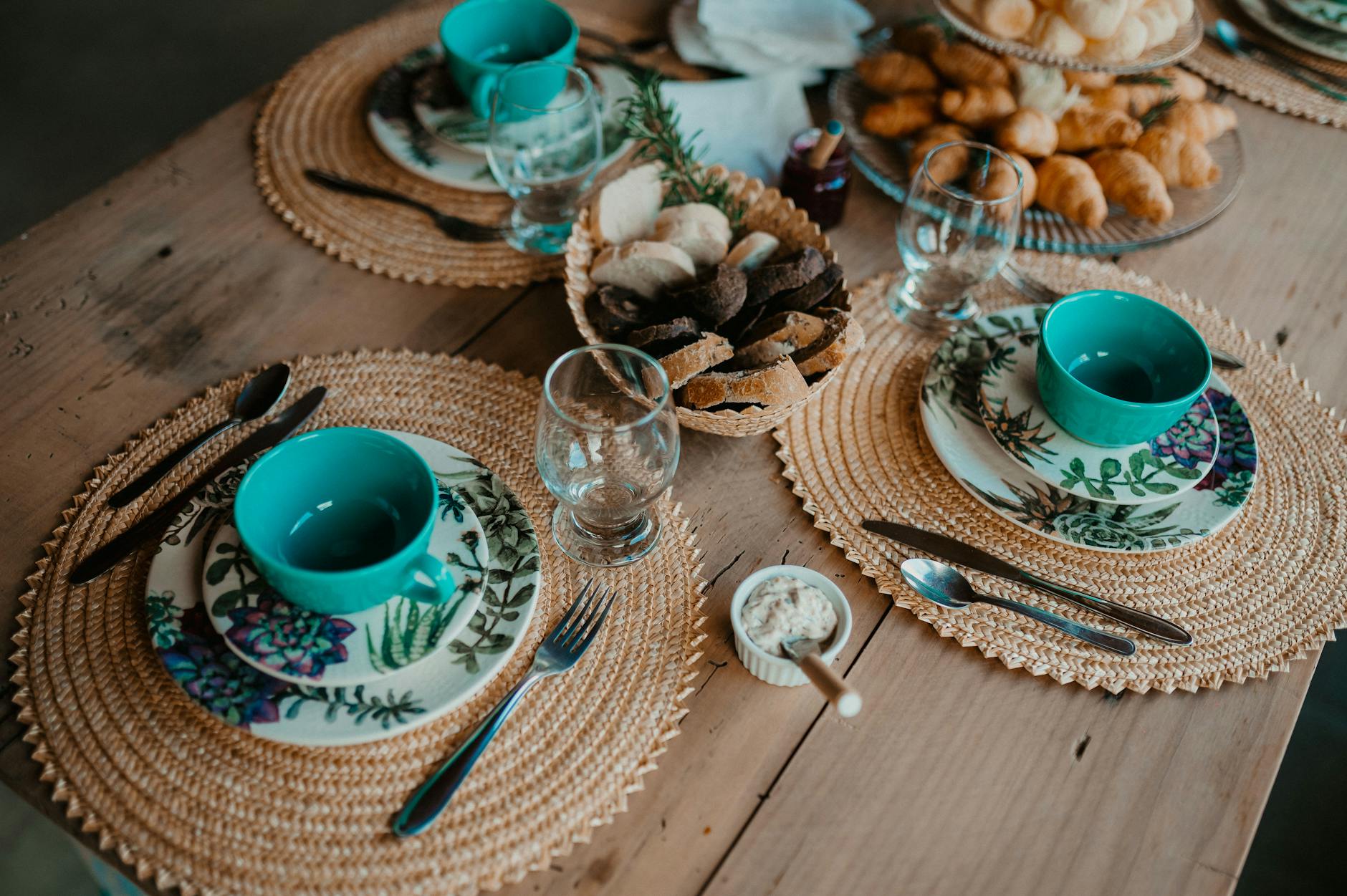 Rustykalny stół zastawiony pieczywem i talerzami w kwiaty